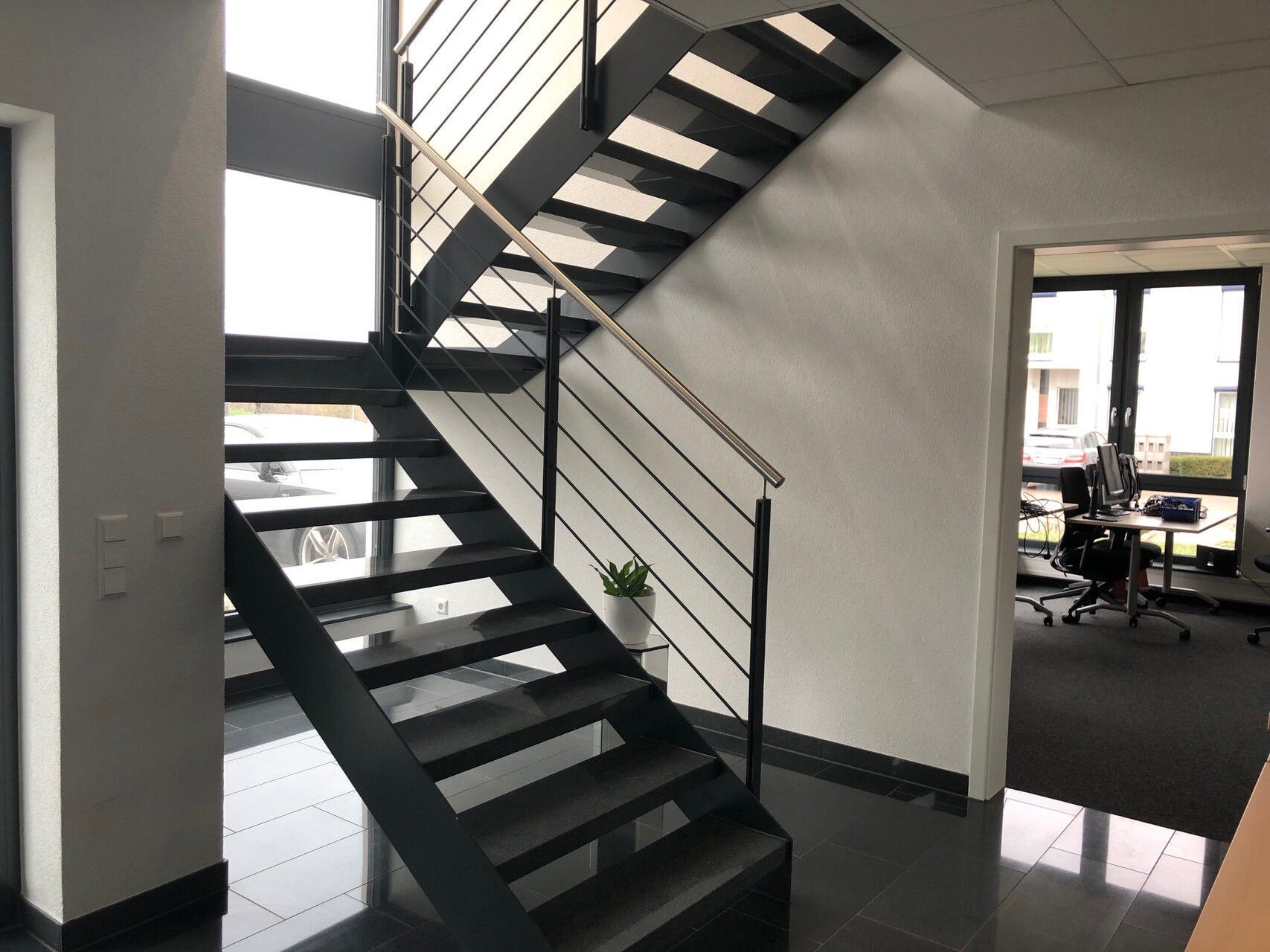 Eine schwarze Treppe mit einem Metallgeländer führt in den zweiten Stock eines Gebäudes.
