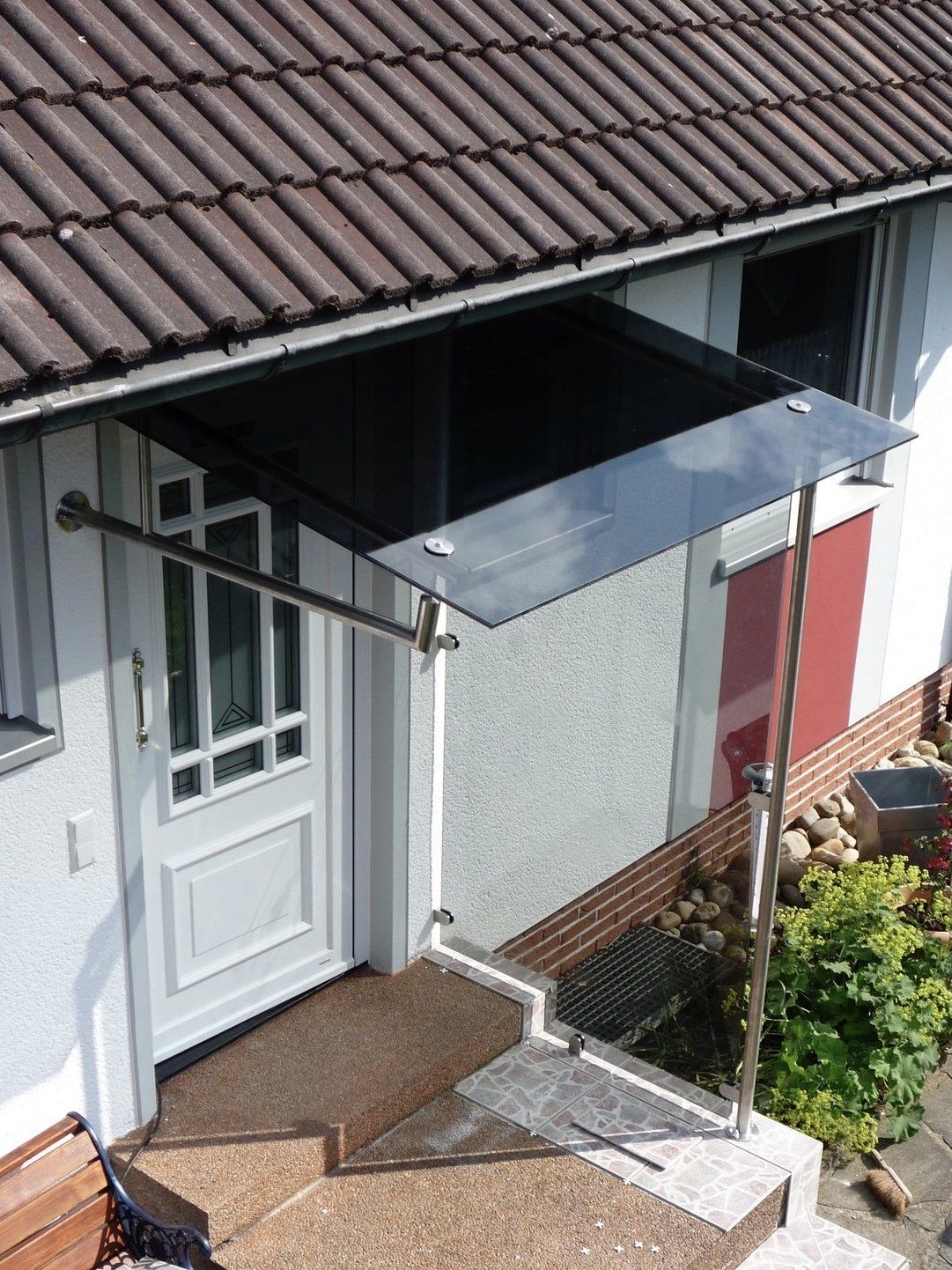 Die Vordertür eines Hauses mit einem Glasdach darüber.