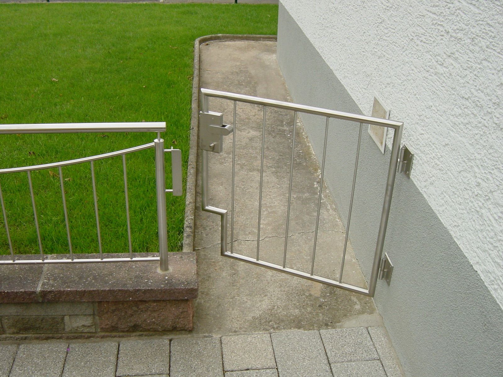 Vor einem Haus ist ein Edelstahltor geöffnet