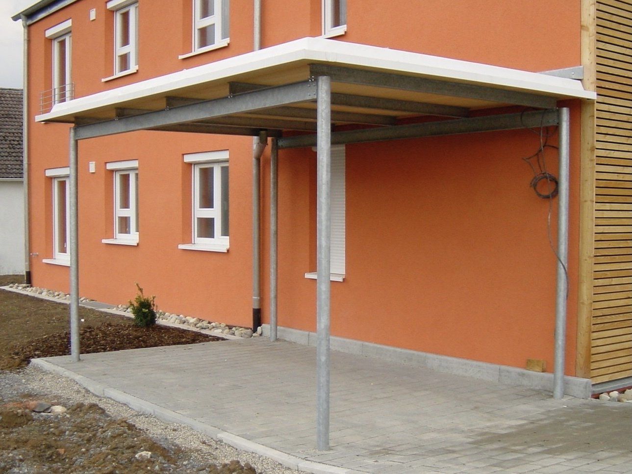 Ein orangefarbenes Haus mit einer Metallveranda an der Seite