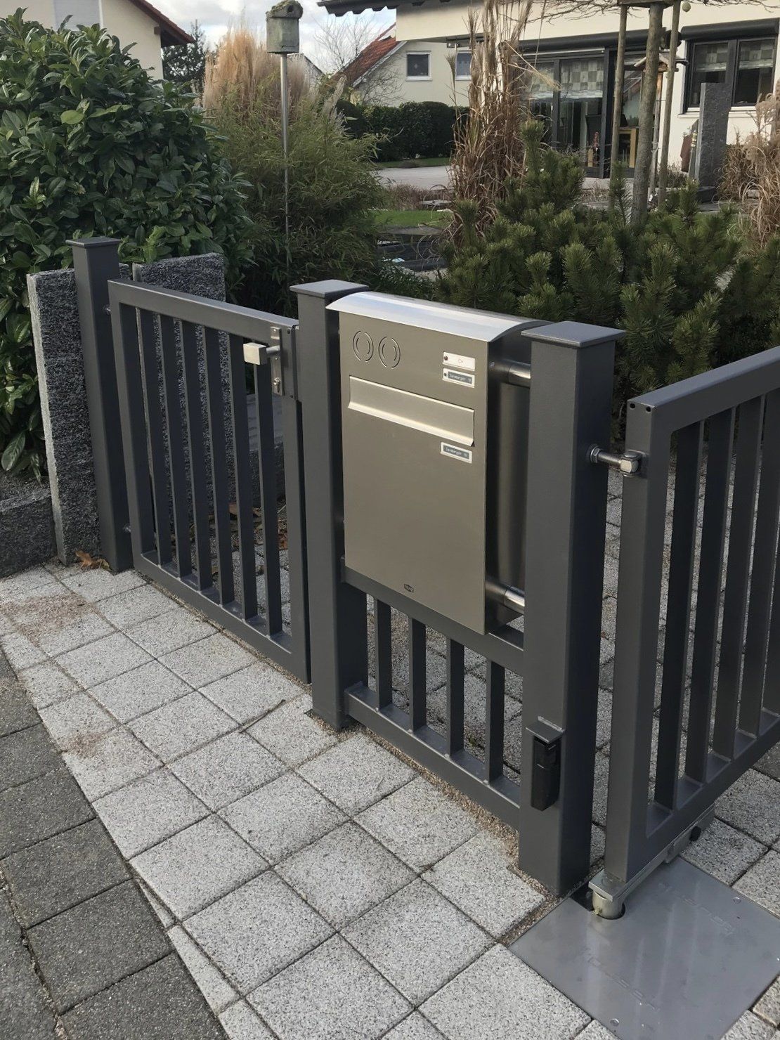 Ein Zaun mit einem daran befestigten Briefkasten und einem Tor.