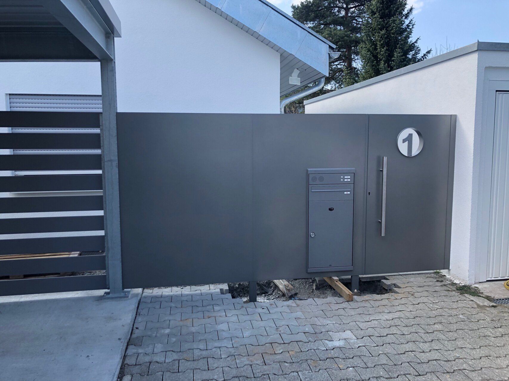 Ein grauer Zaun mit einem Briefkasten davor
