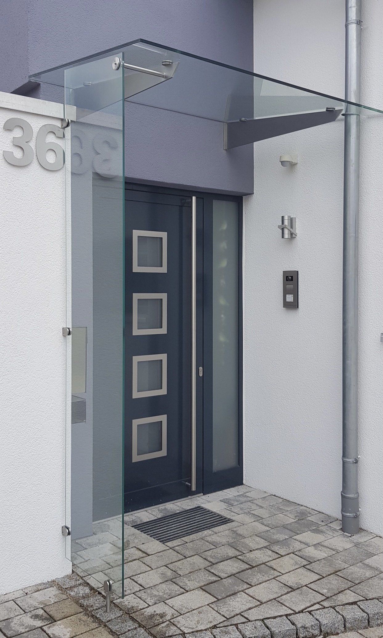 Die Vordertür eines Hauses mit einem Glasdach darüber.