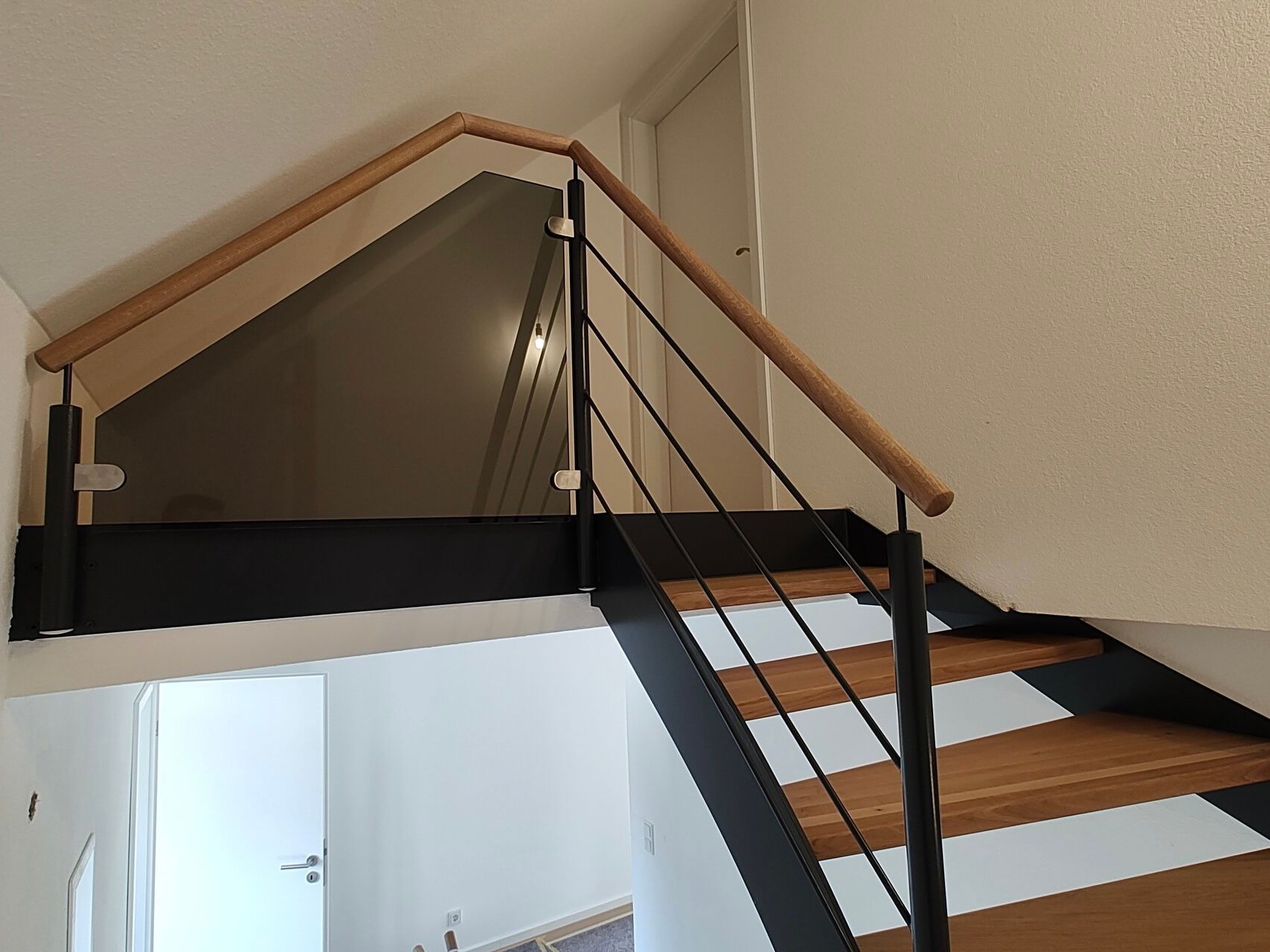 Eine Treppe mit einem Holzgeländer und einem Glasgeländer in einem Haus.