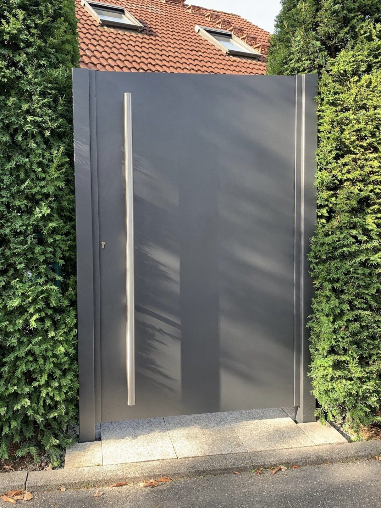 Ein graues Metalltor mit einem Edelstahlgriff