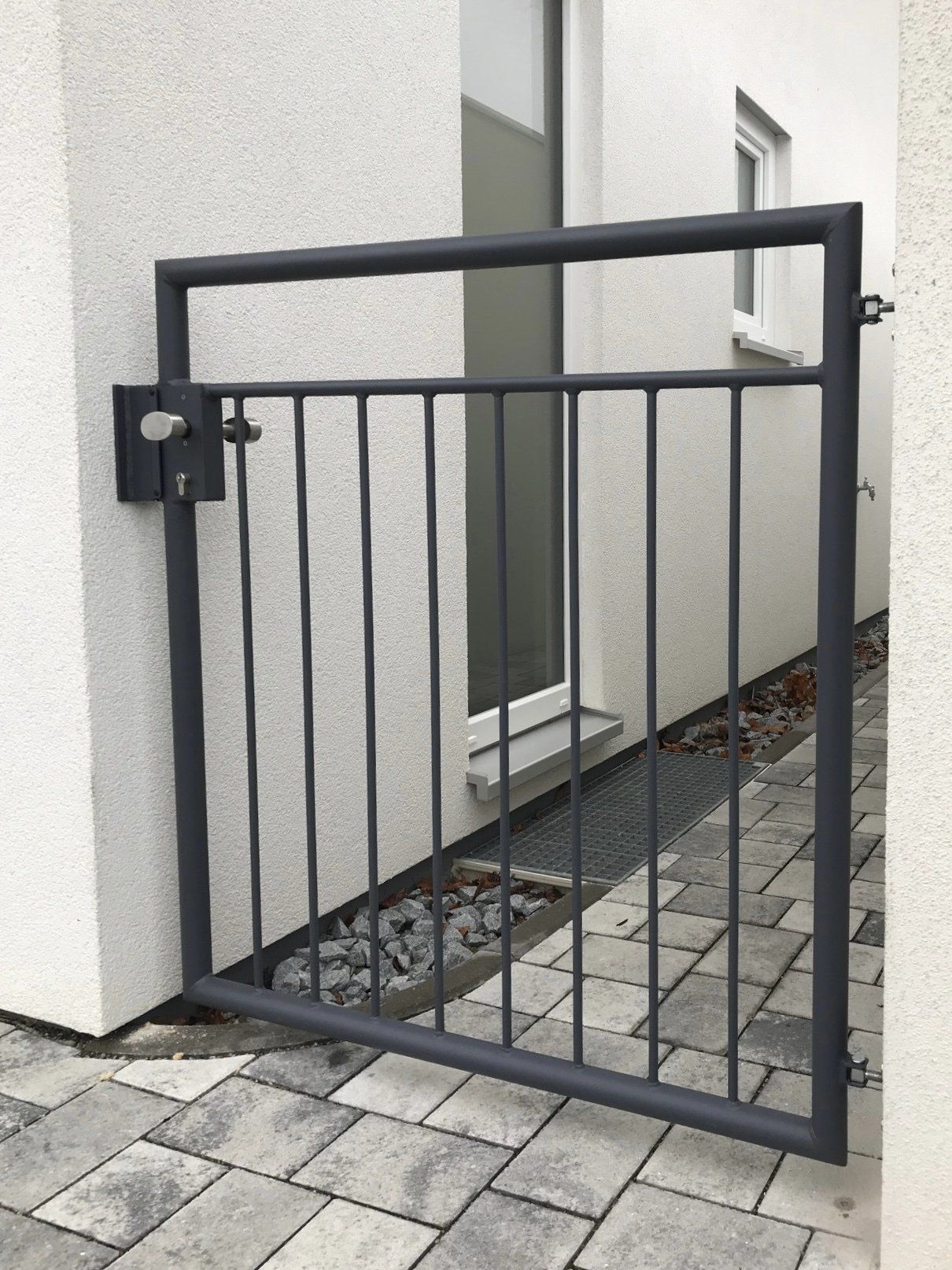 Vor einem weißen Gebäude steht ein schwarzes Tor.