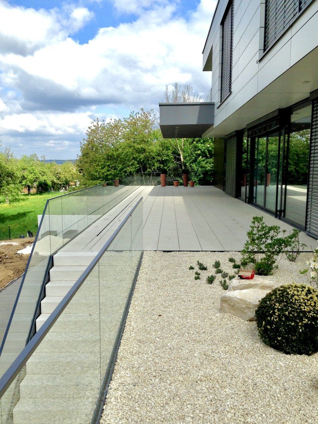 Eine Terrasse mit einem Glasgeländer und einer Treppe, die dorthin führt