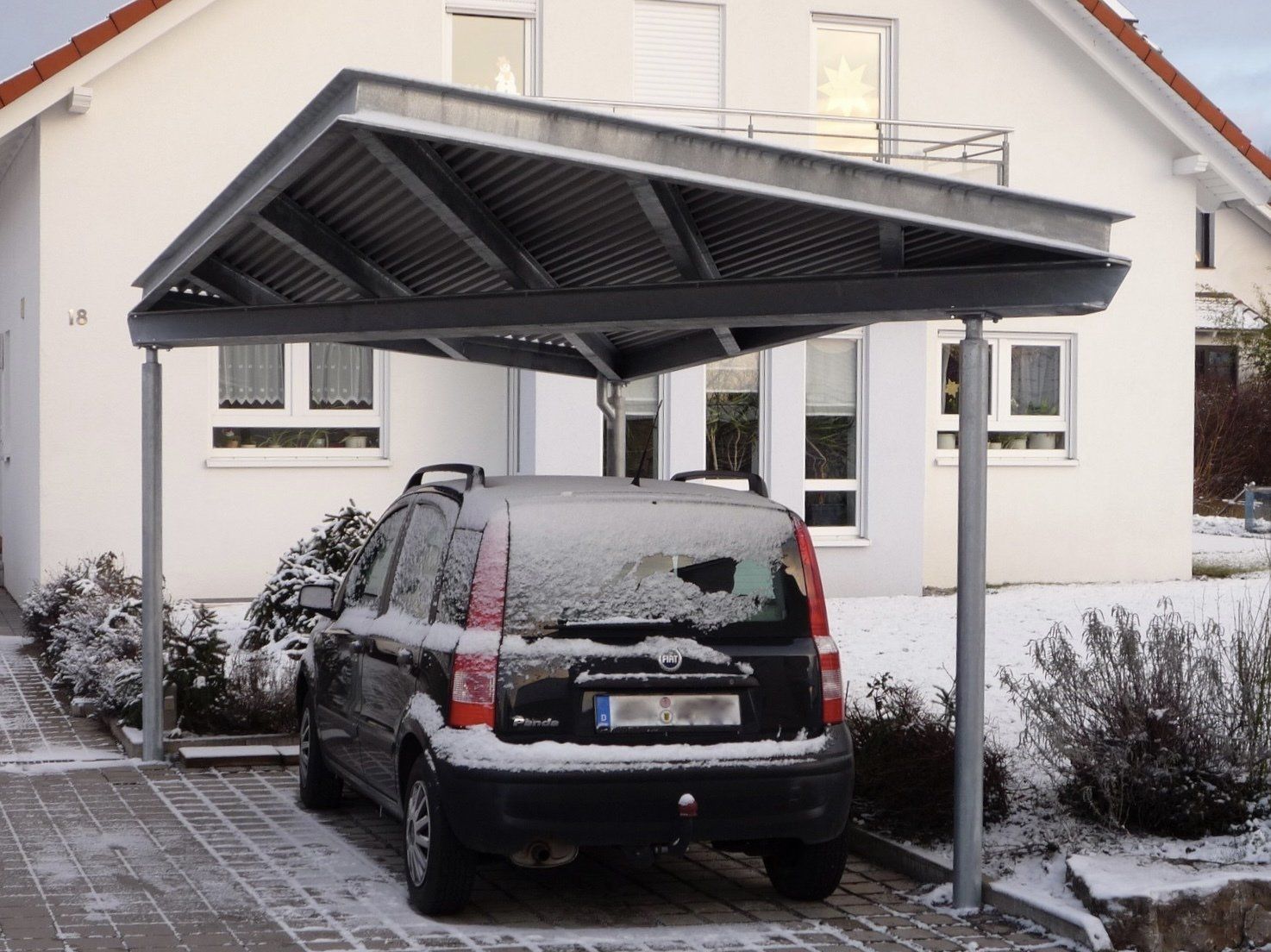 Ein Auto ist unter einem Carport vor einem Haus geparkt