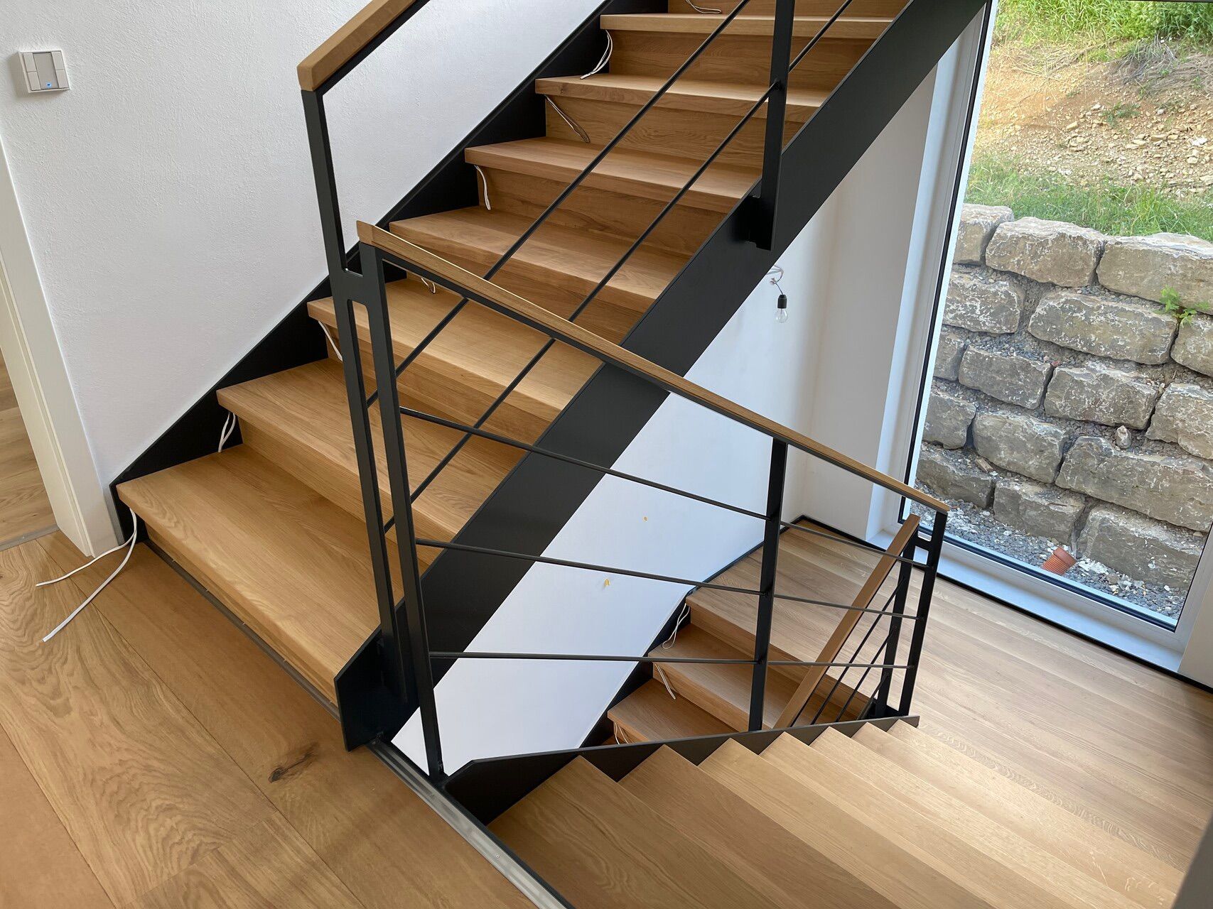 Eine Treppe mit Holzstufen und einem schwarzen Geländer in einem Haus.