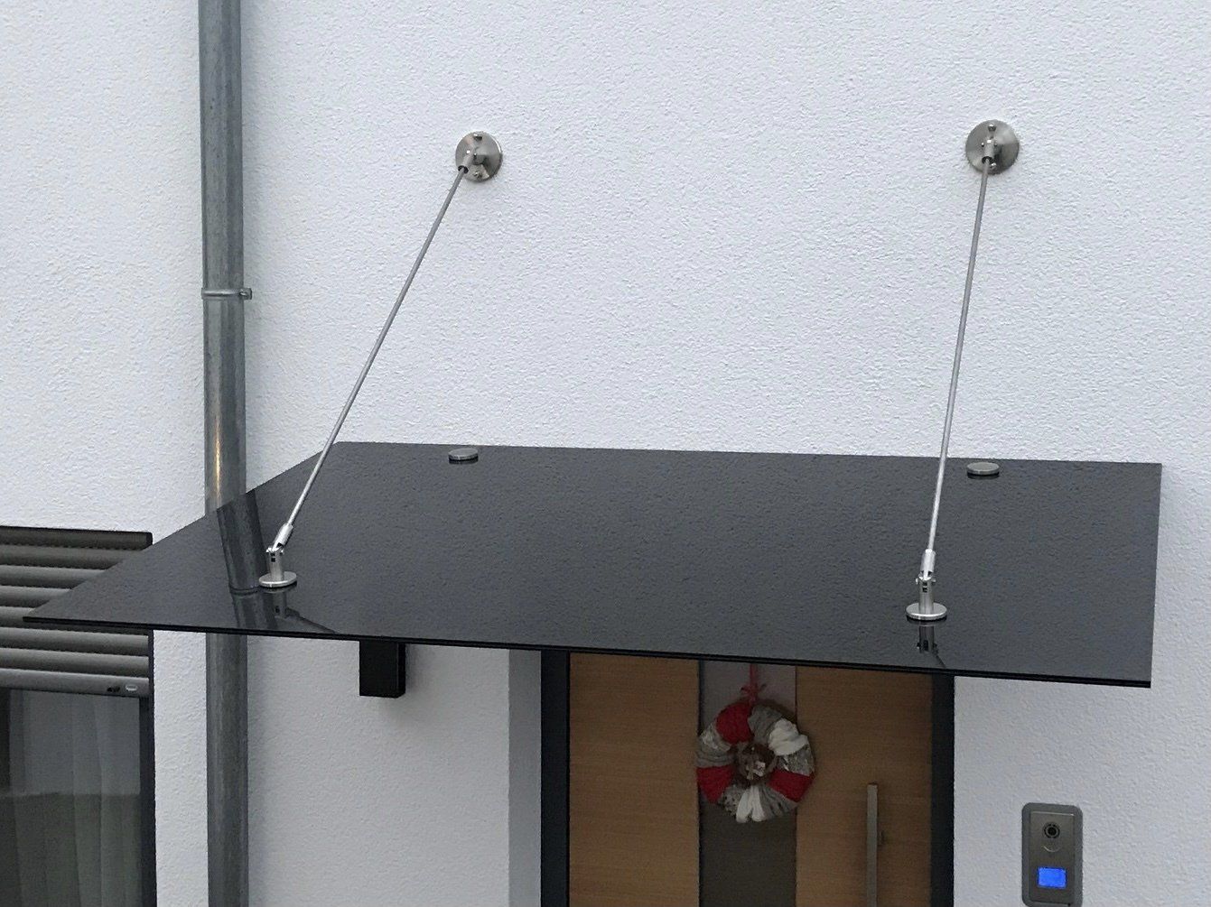 Eine Tür mit einem Baldachin darüber und einem Kranz darauf.