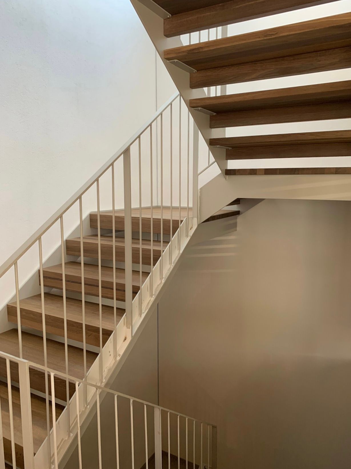 Die Treppe besteht aus Holz und Metall und hat ein weißes Geländer.