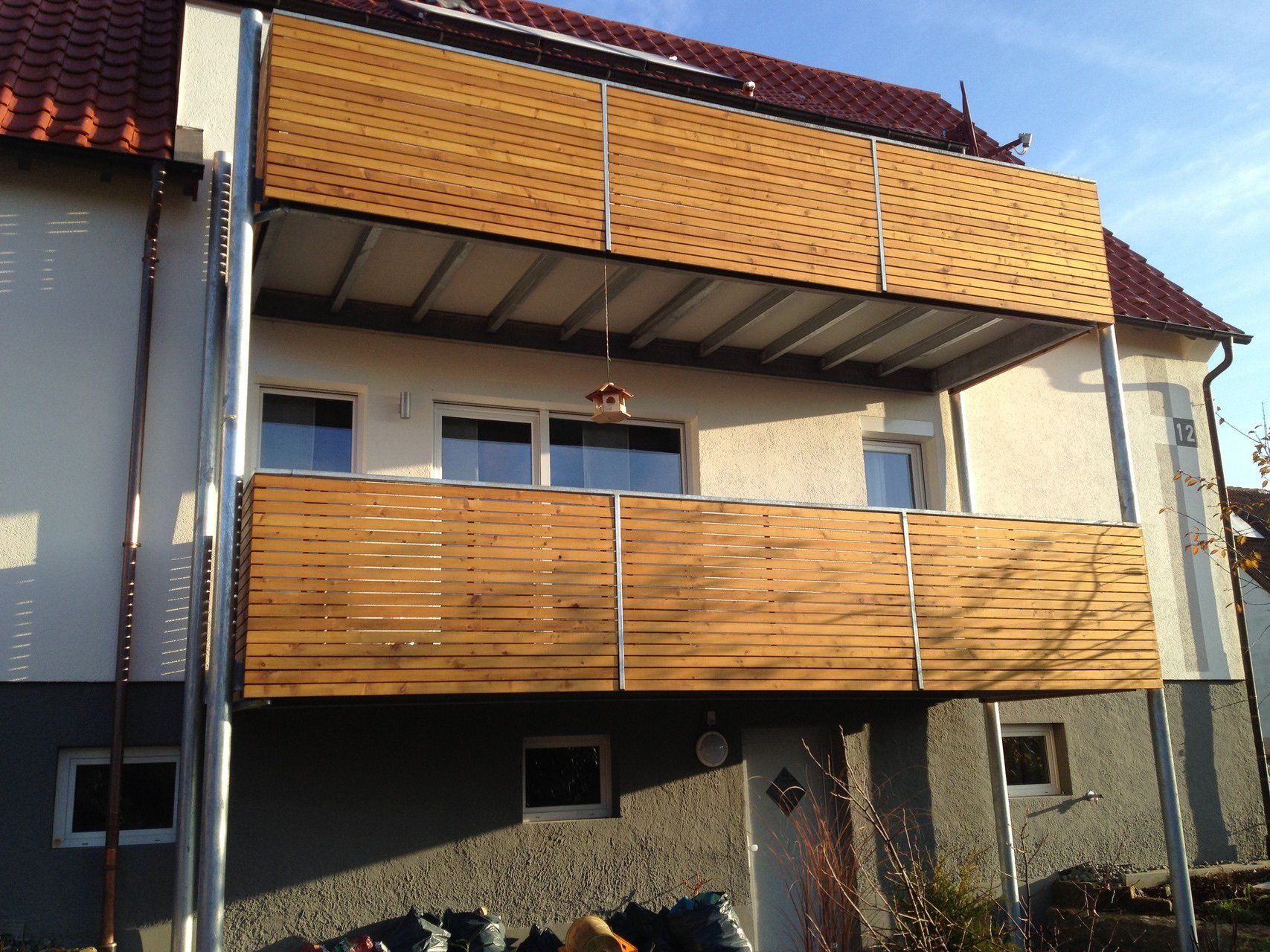 Ein weißes Haus mit einem Holzbalkon im zweiten Stock