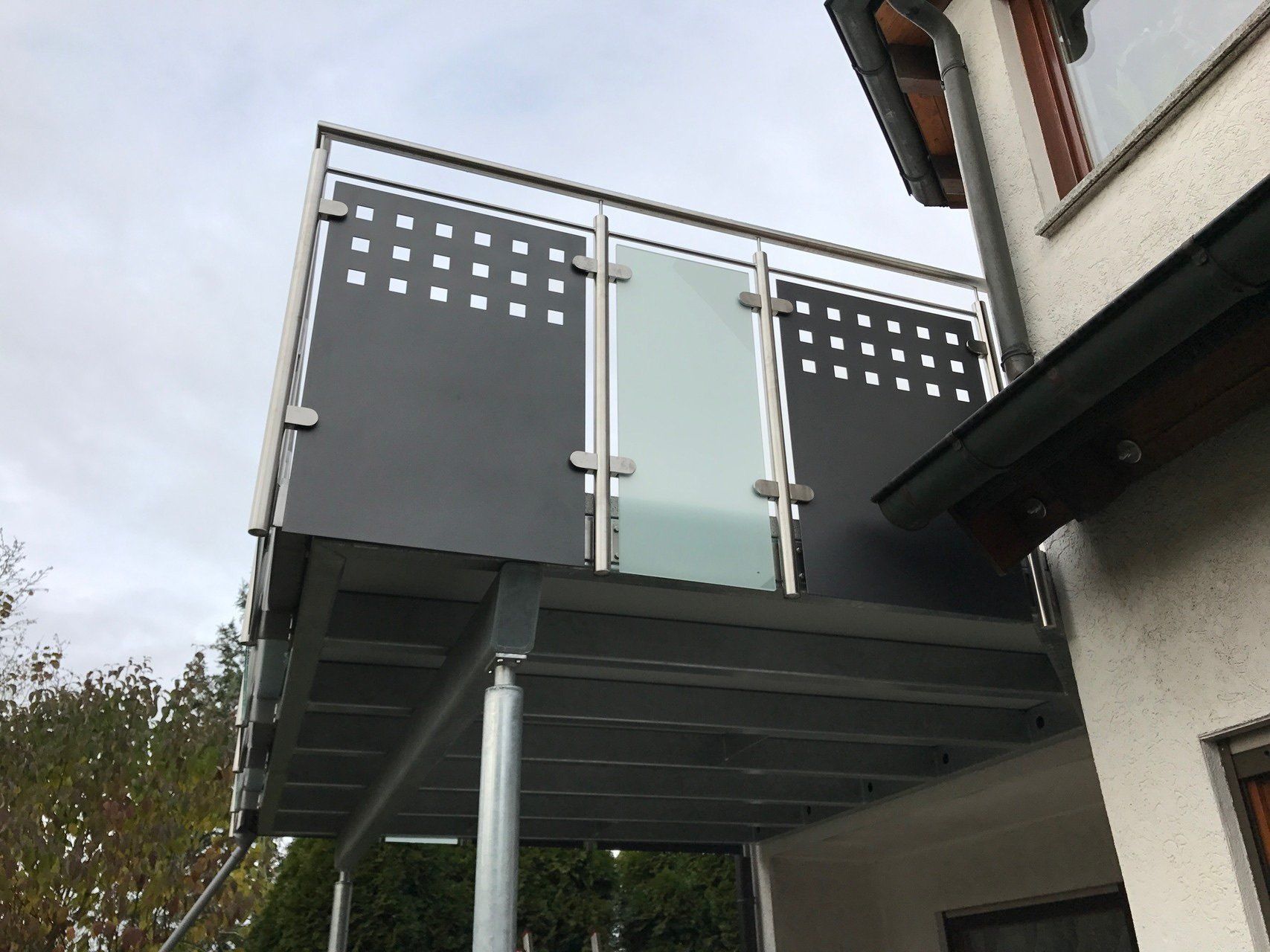 An der Seite eines Gebäudes ist ein Balkon mit einem Geländer aus Edelstahl angebracht.