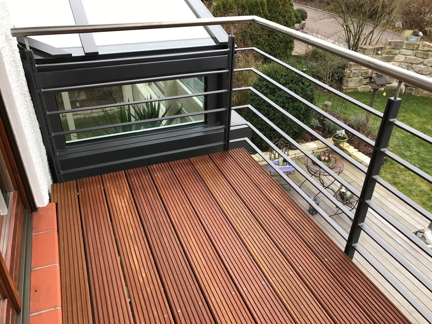 Ein Balkon mit Holzdeck und Metallgeländer.