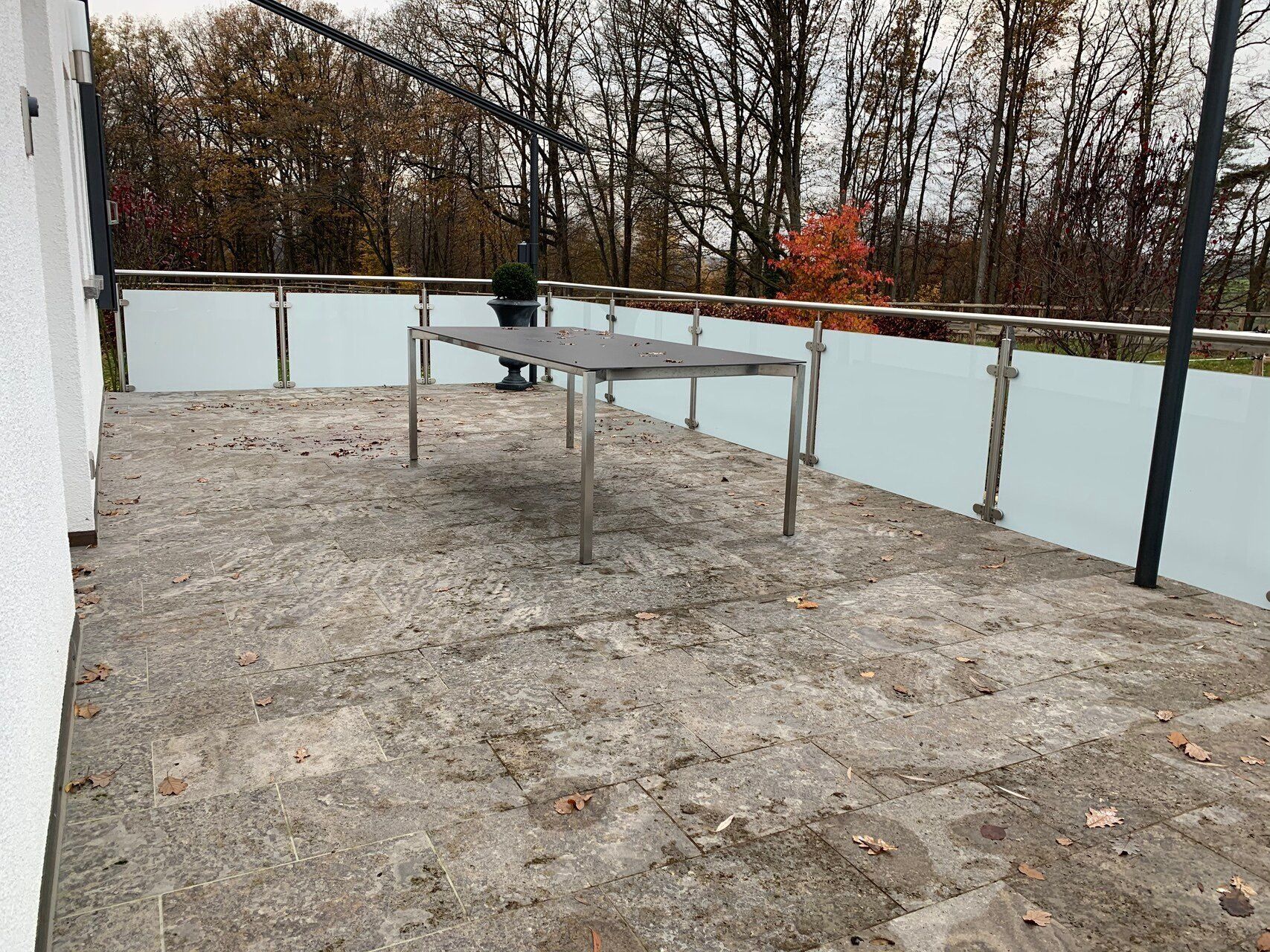Eine Terrasse mit einem Tisch und Bäumen im Hintergrund