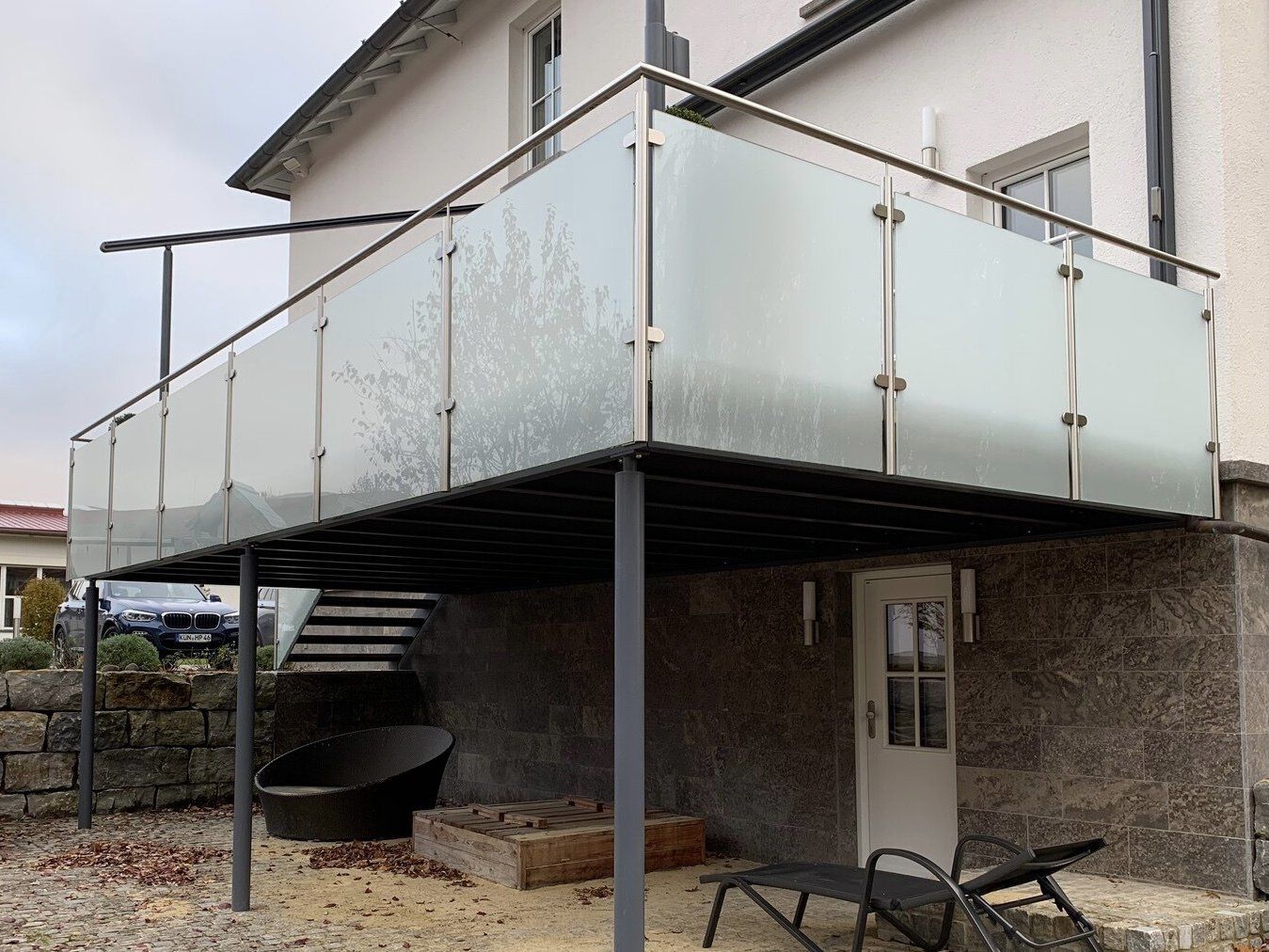 Ein Balkon mit einem Glasgeländer an der Seite eines Hauses