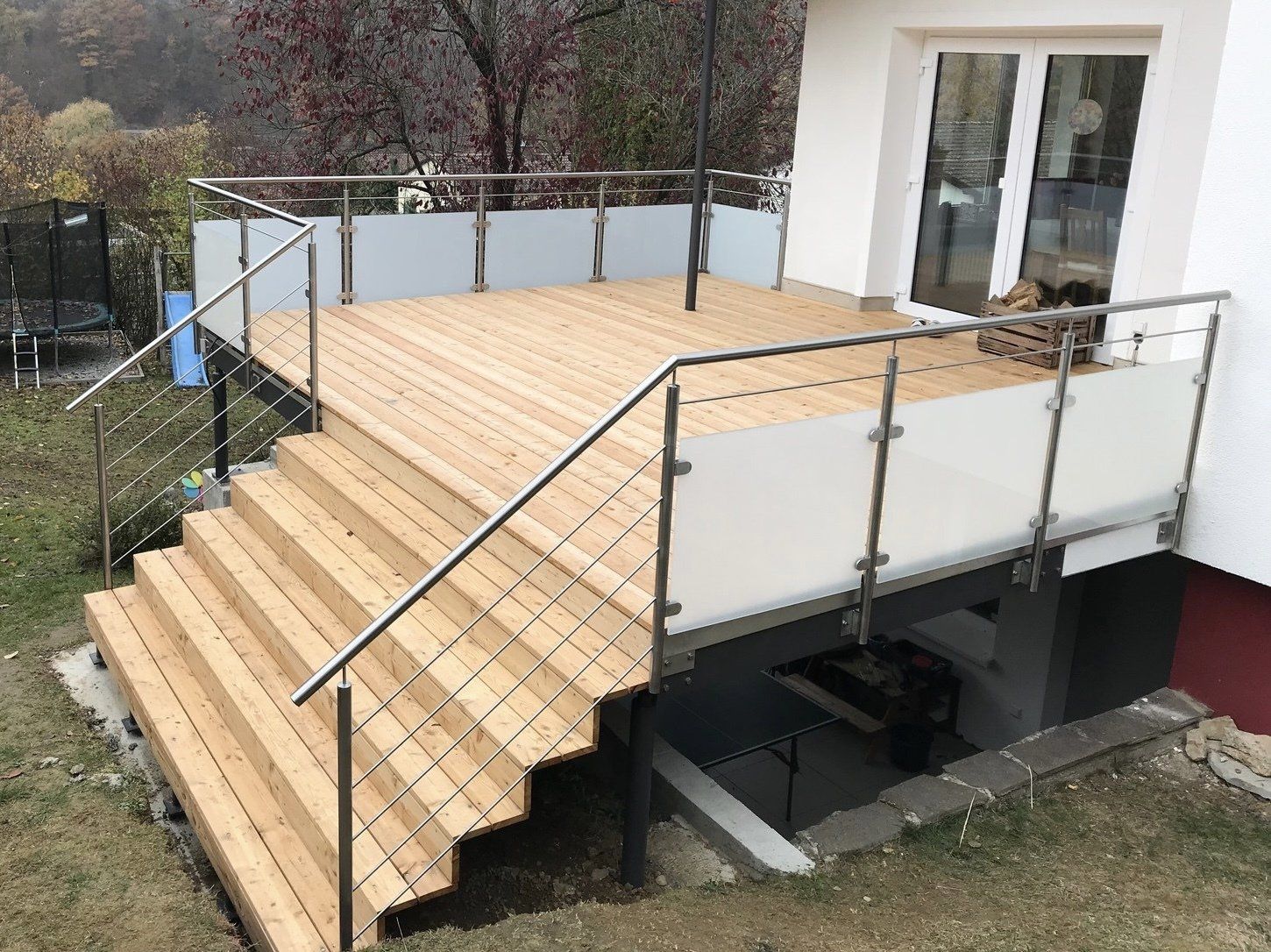 Ein Holzdeck mit Treppe und Edelstahlgeländer