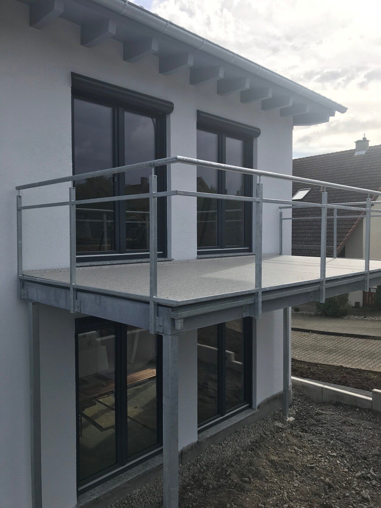 Ein weißes Haus mit einem Balkon an der Seite.