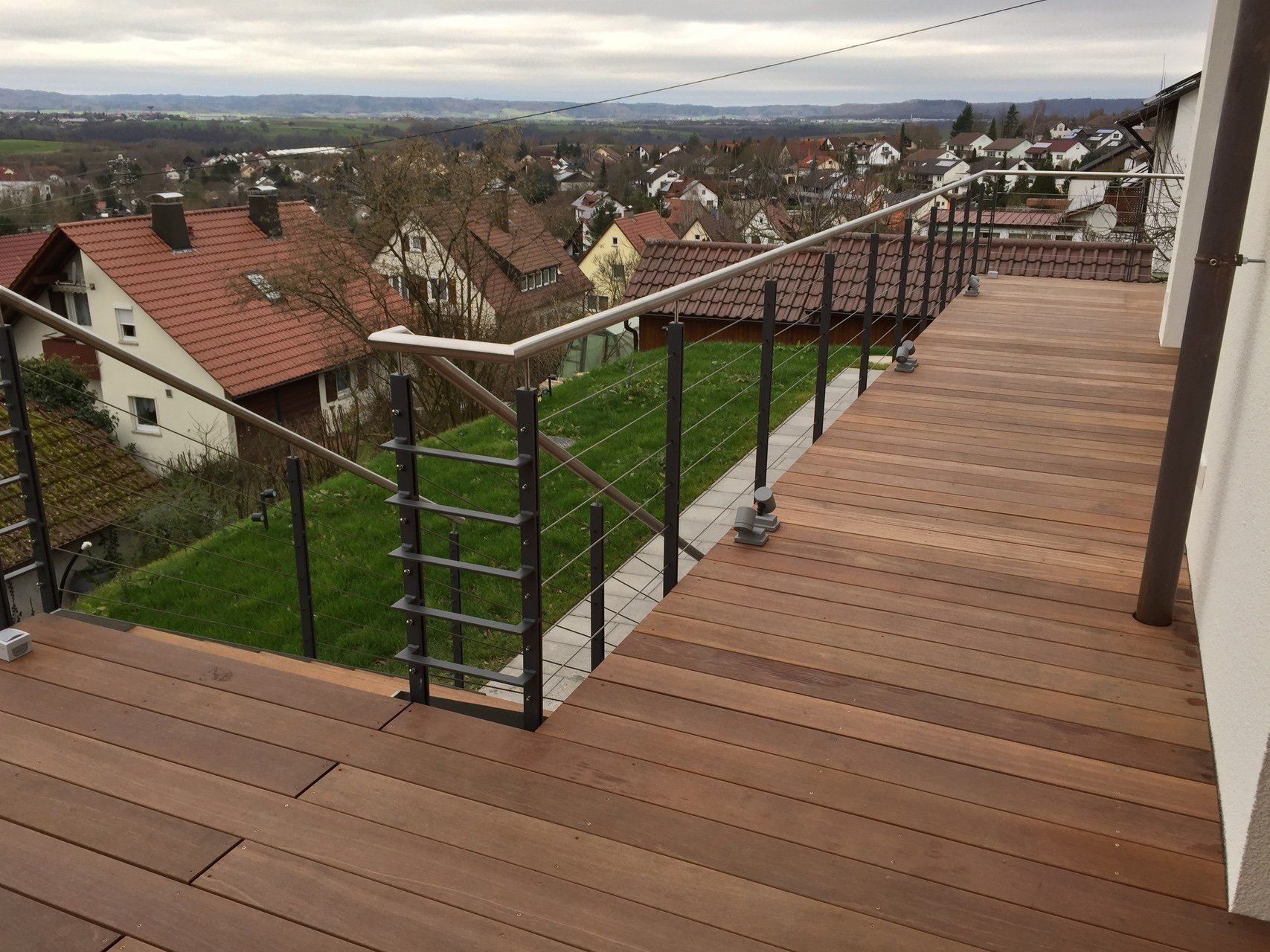 Ein Holzdeck mit einem Metallgeländer und einer Treppe, die dorthin führt.