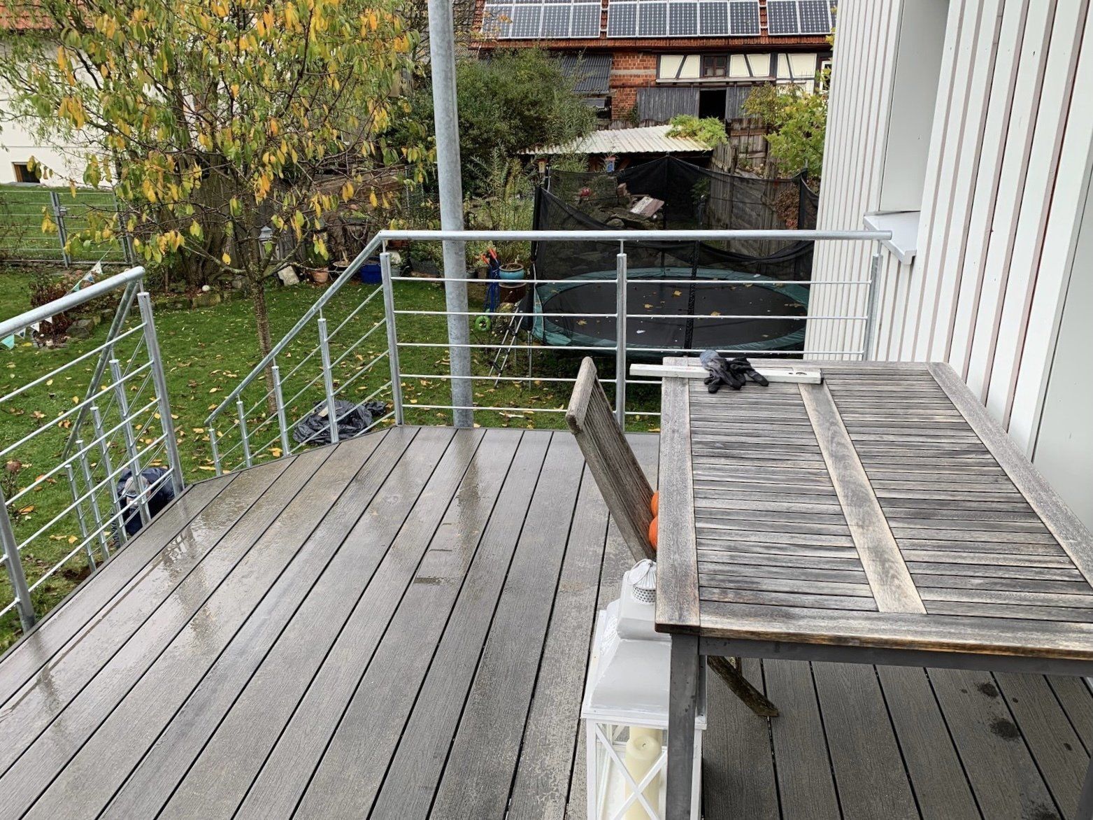 Eine Holzterrasse mit Tisch und Stühlen und einem Metallgeländer.