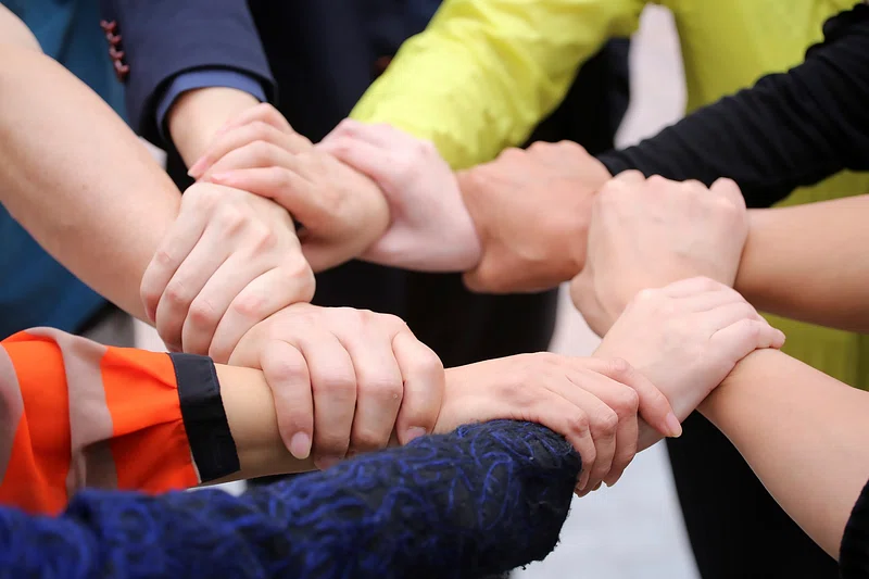 Eine Gruppe von Menschen legt ihre Hände zu einem Kreis zusammen