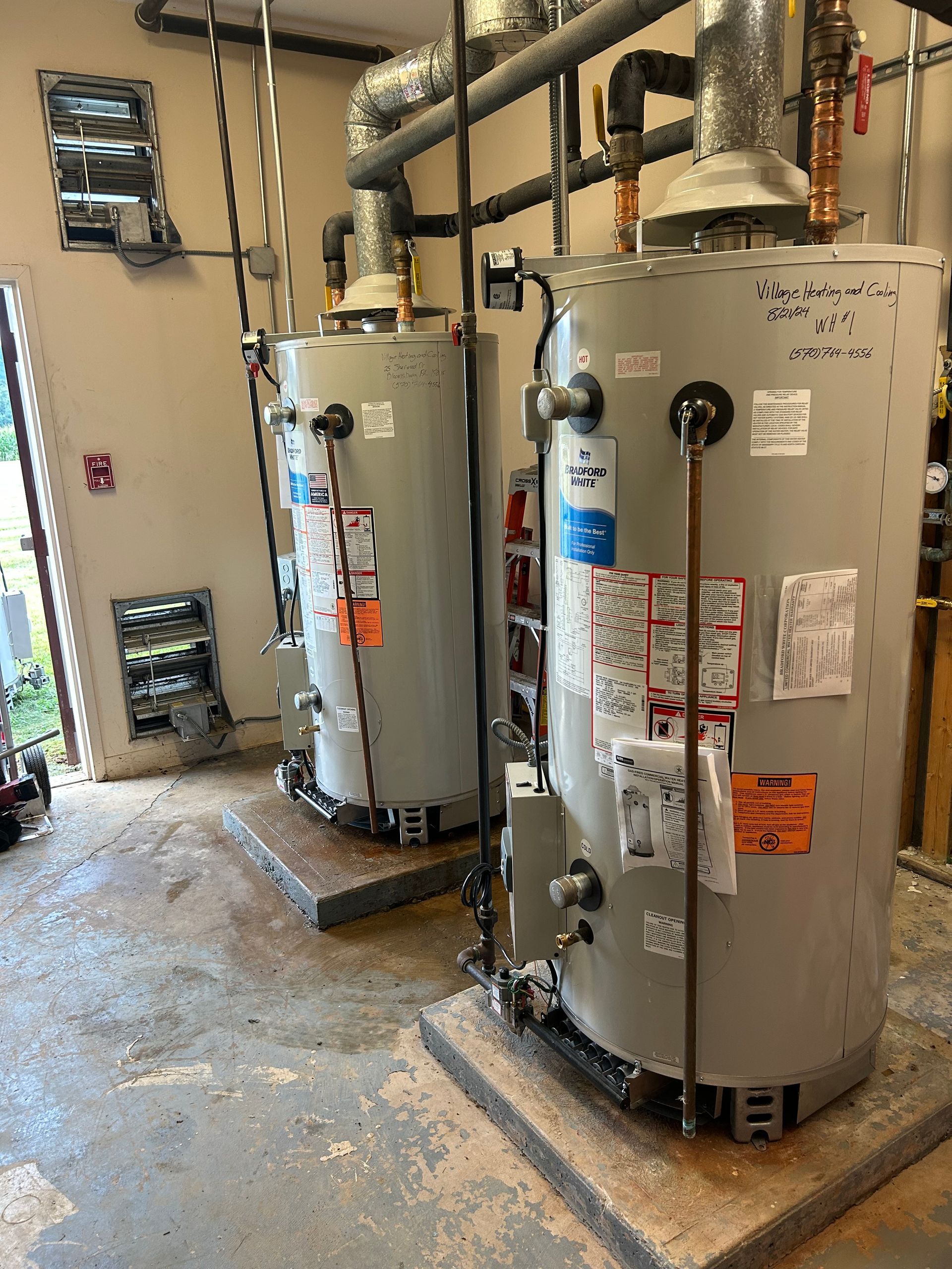 Water heater in a garage, surrounded by water, with pipes and controls visible.