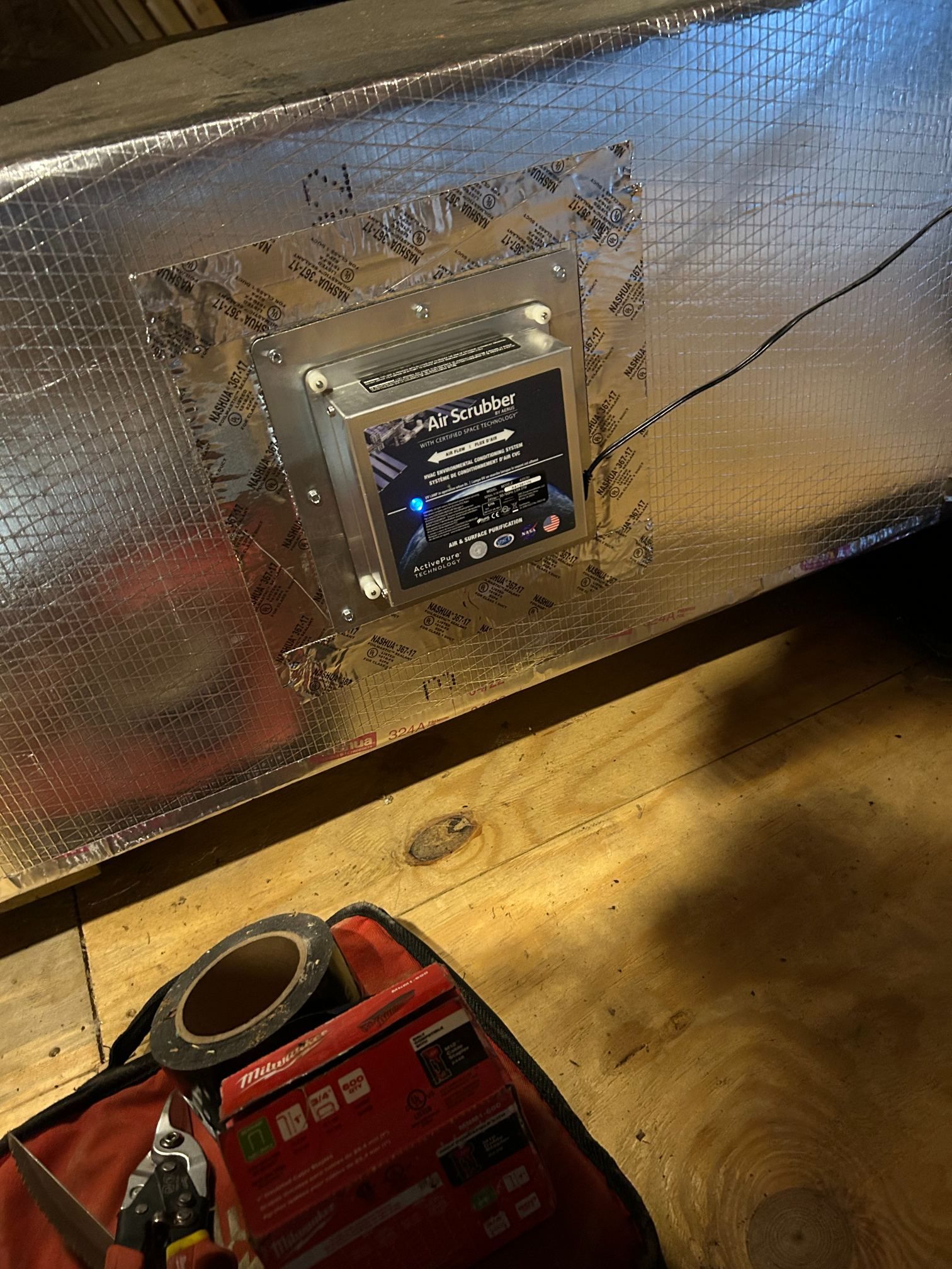 Red portable machine beside a reflective insulated panel with a small digital control unit mounted on it.