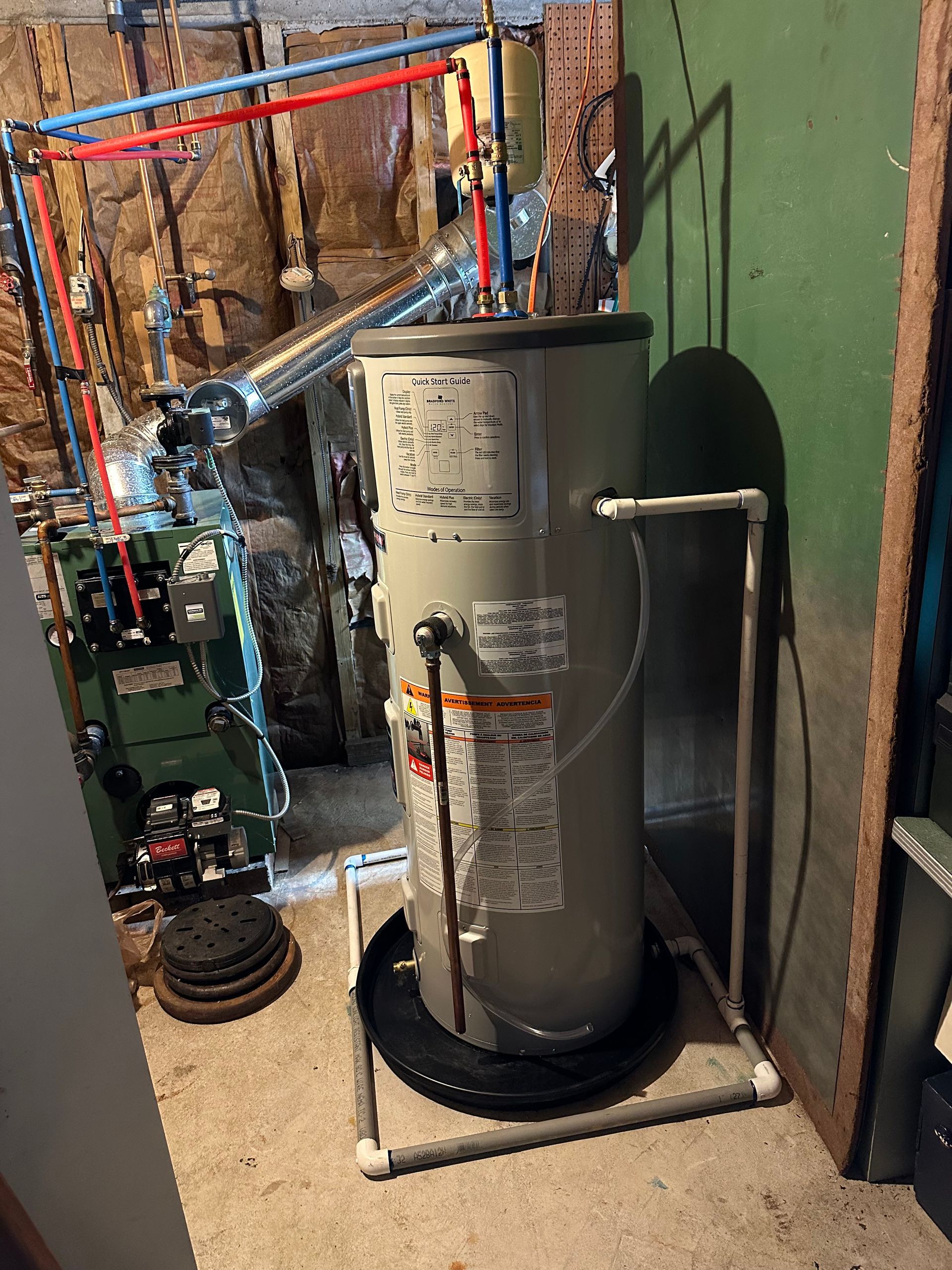 Utility room with a gray water heater, copper pipes, and exposed wall insulation.
