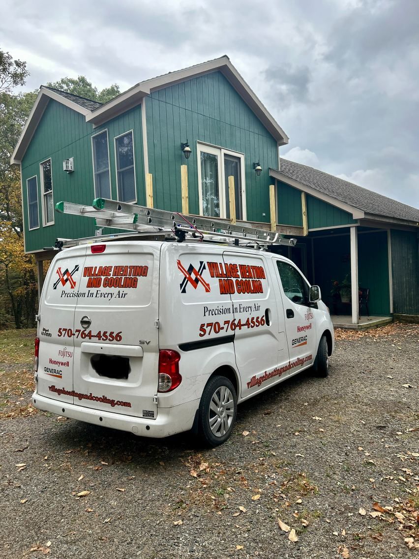 White service van parked in front of a green house and garage, with business lettering on the side.