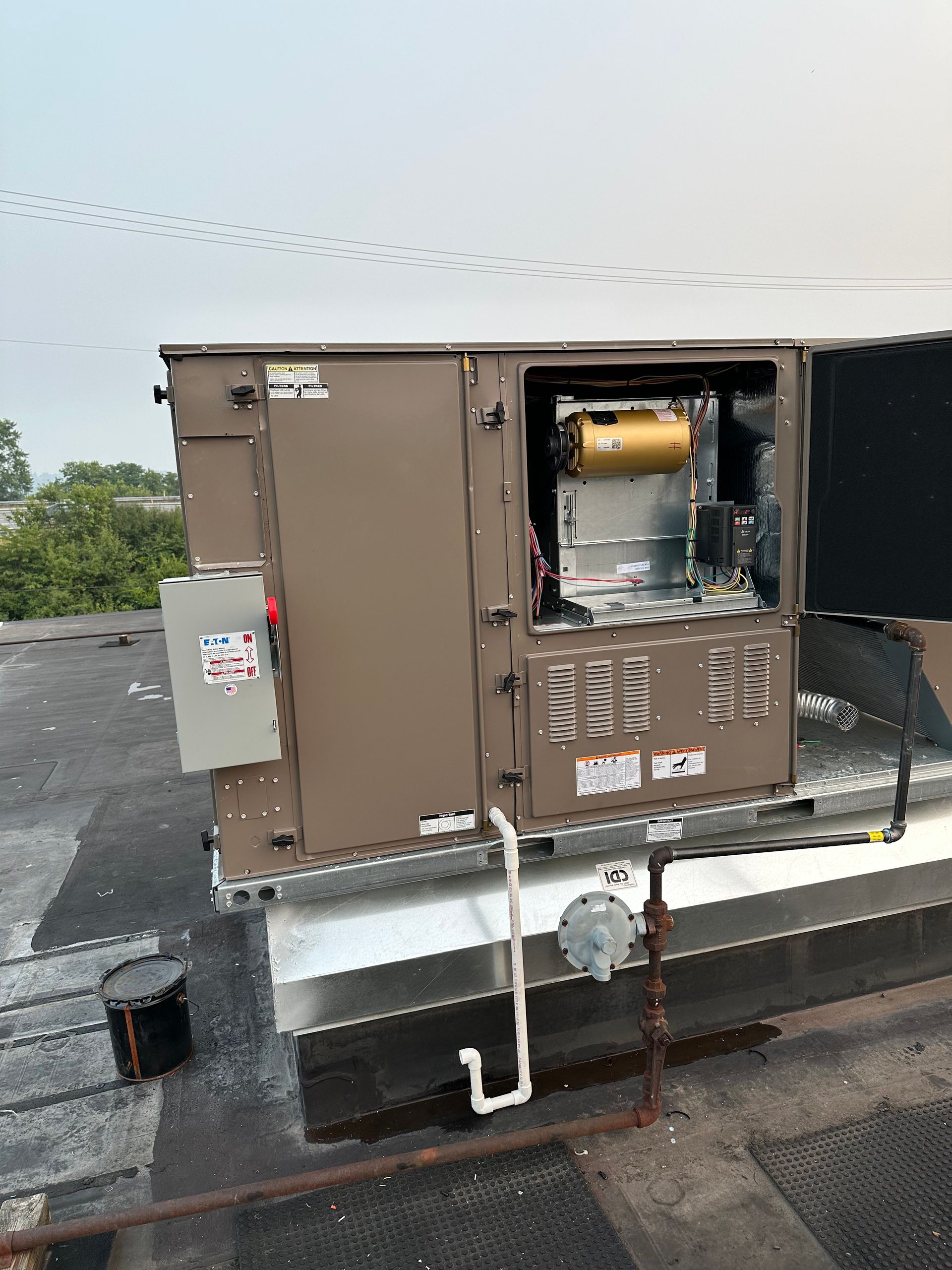 HVAC unit open on a rooftop, with tools and equipment visible.