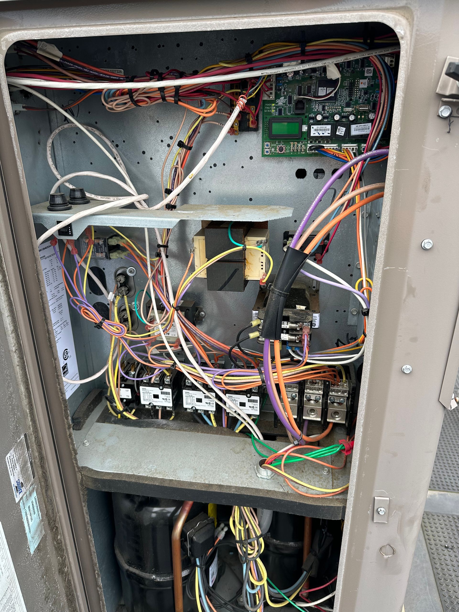 Open electrical control box with wires, circuit boards, and relays.