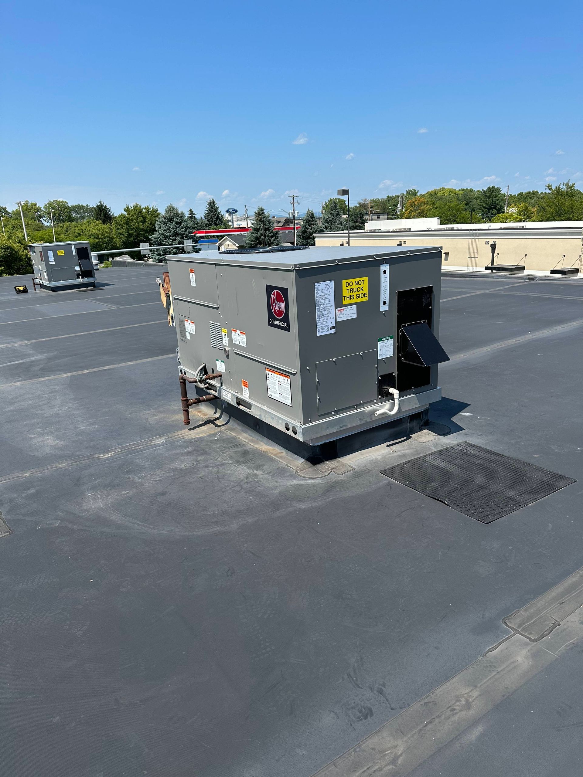 Gray rooftop HVAC unit on a flat roof under a clear blue sky