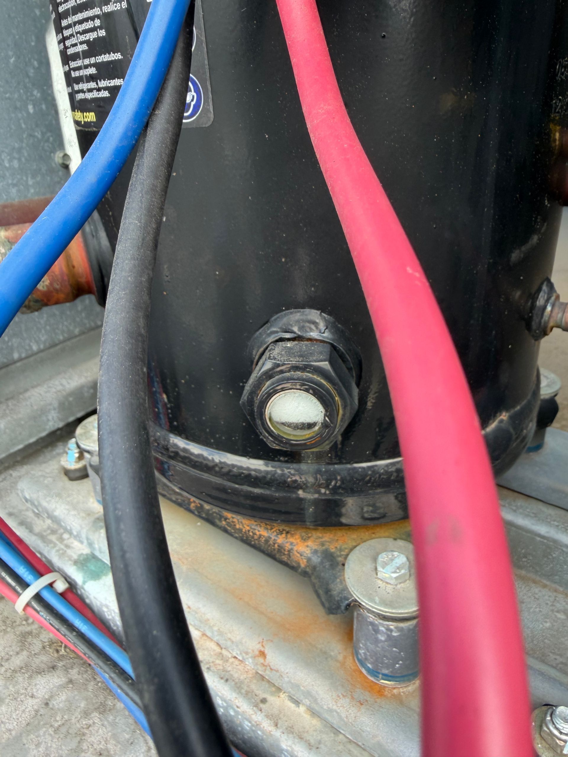 Close-up of black cylindrical equipment with red and blue cables and a bolt at the base.