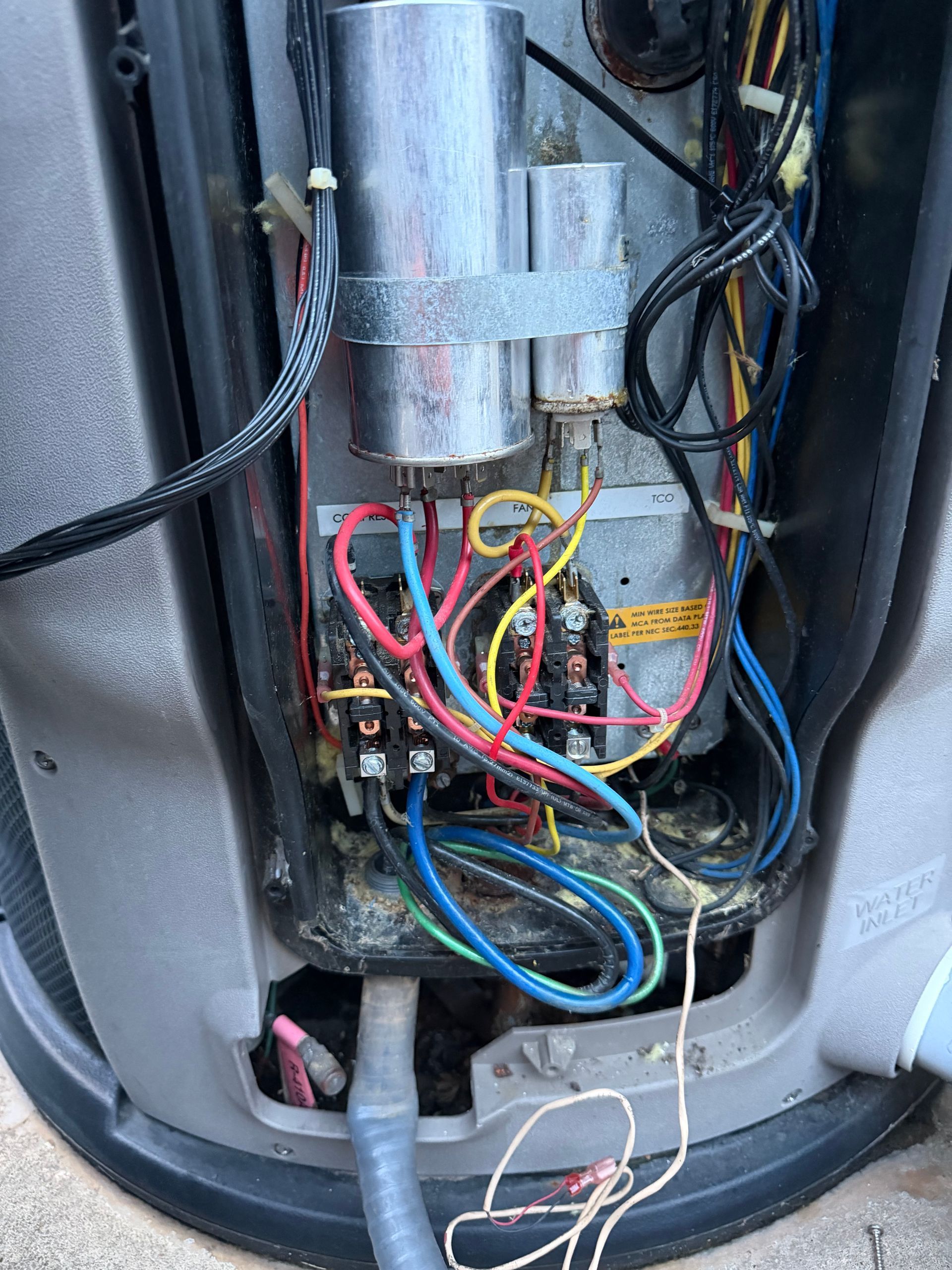 Open electrical panel with bundled red, blue, yellow, and black wires inside a metal housing