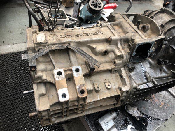A dirty engine block is sitting on a table in a garage.