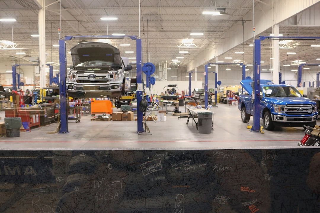 Cars on lifts in a large, well-lit auto repair shop.