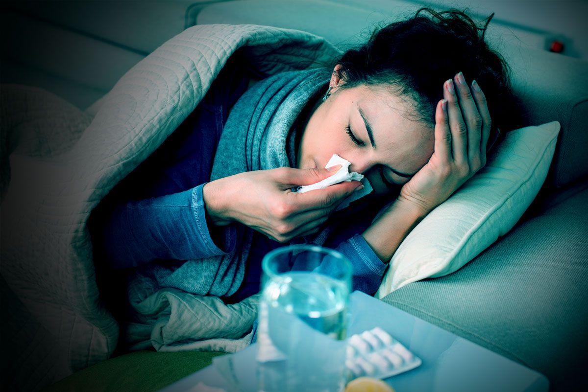 a woman is laying in bed blowing her nose with a napkin .