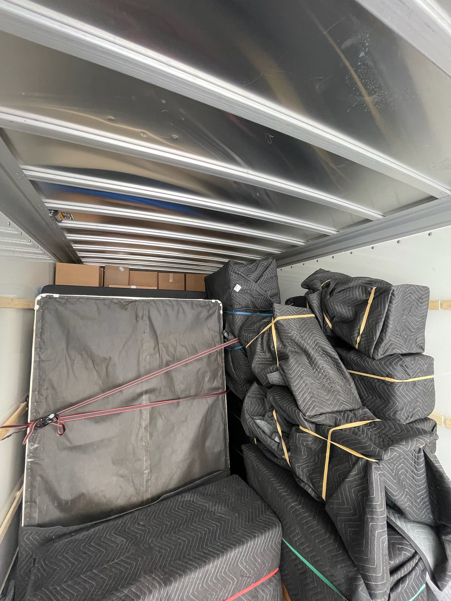 The inside of a moving truck filled with boxes and bags.