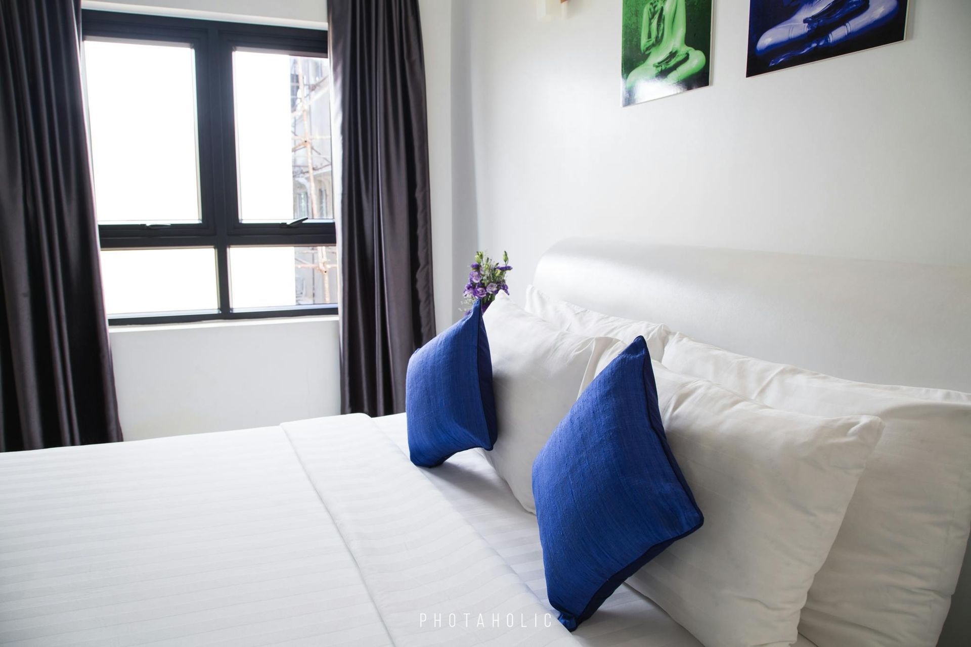 A bed with white sheets and blue pillows in a hotel room.