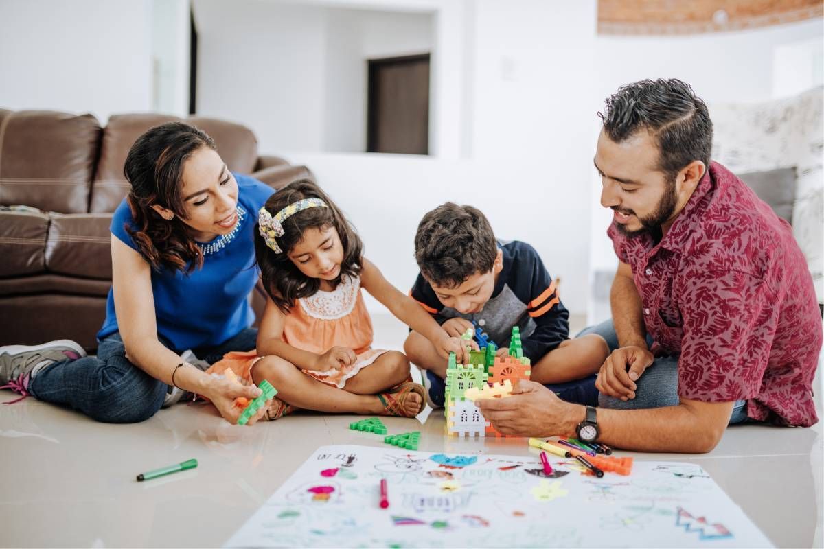 Family building a tower with colorful blocks on a living room floor.