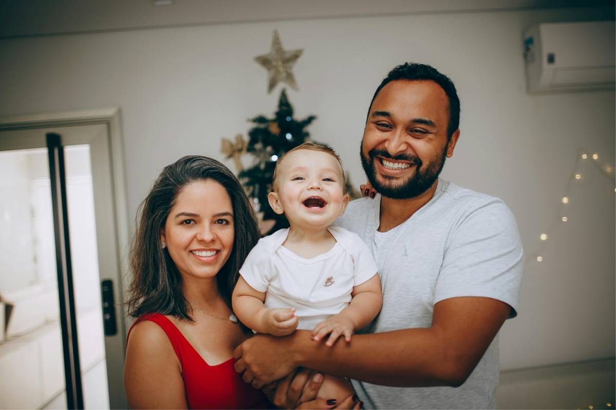 Family smiling and the baby is in the father's arms.