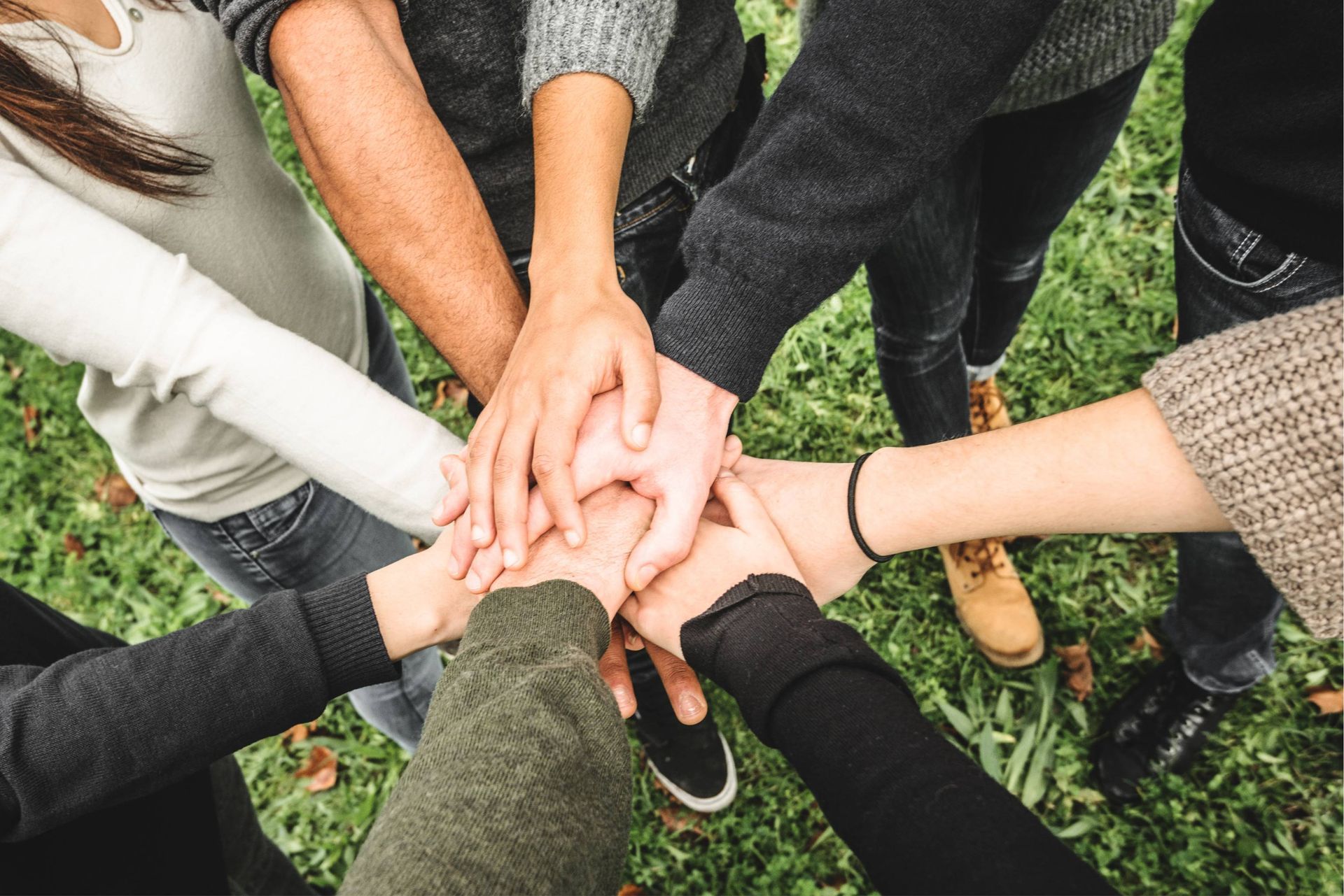 Hands stacked together in a circle, symbolizing unity and teamwork.