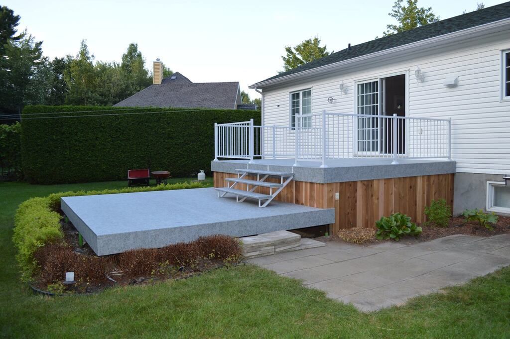 Une maison blanche avec une terrasse en pvc et des escaliers devant elle