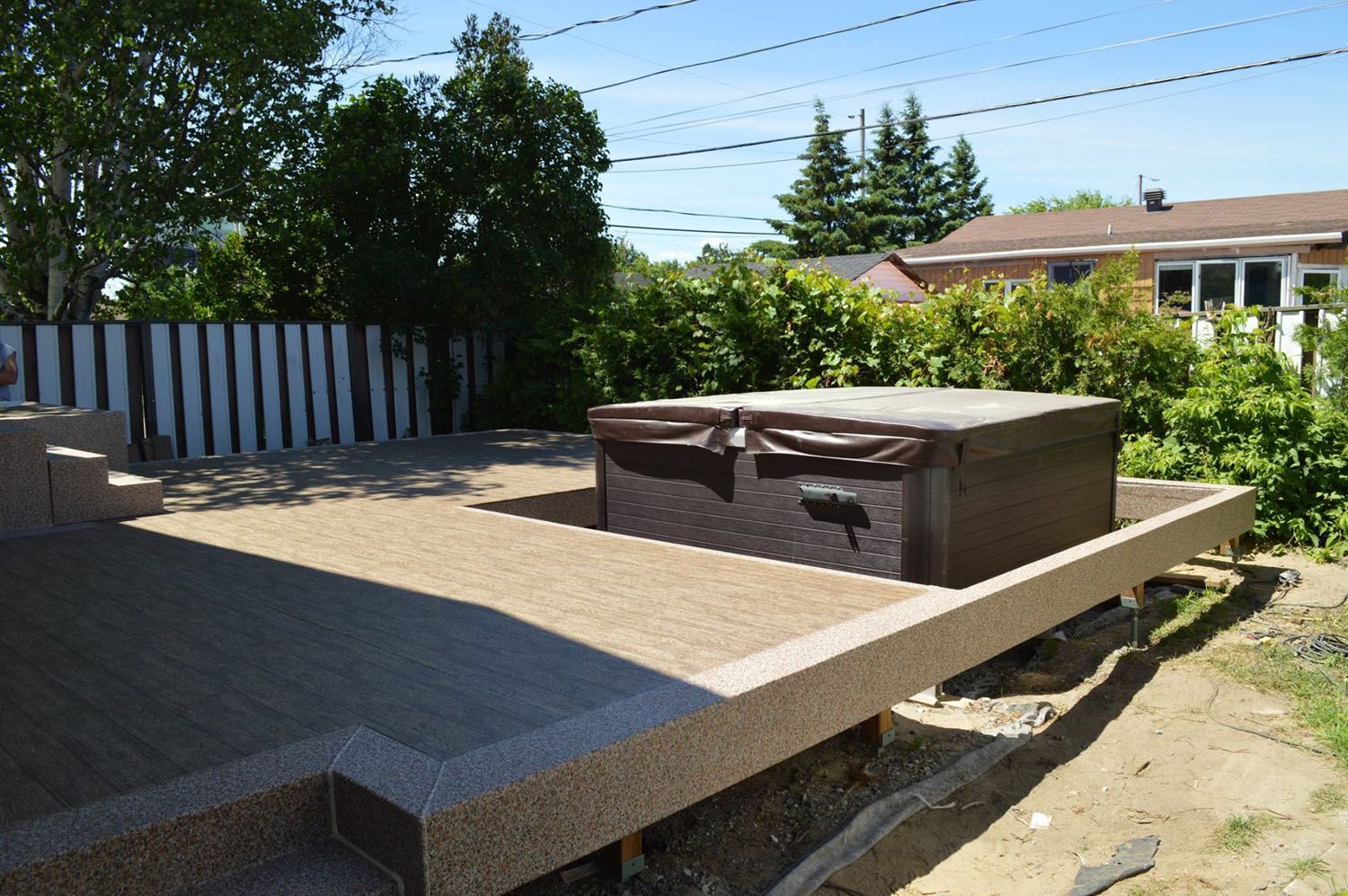 A hot tub is sitting on top of a beige pvc membrane deck