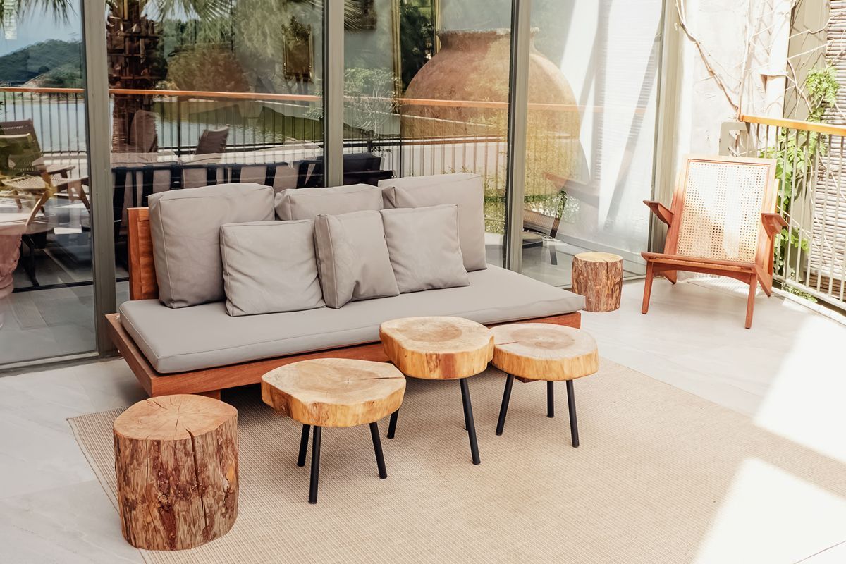 Un patio avec un canapé, des chaises, des tables et des tabourets en souche.