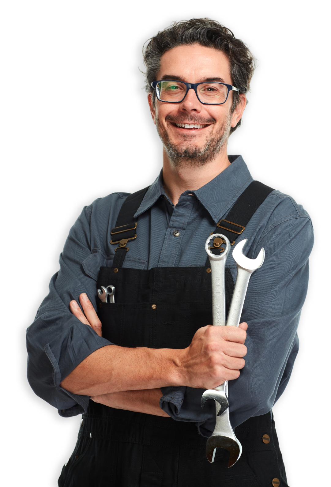Mechanic smiling, holding wrenches, wearing overalls, arms crossed.