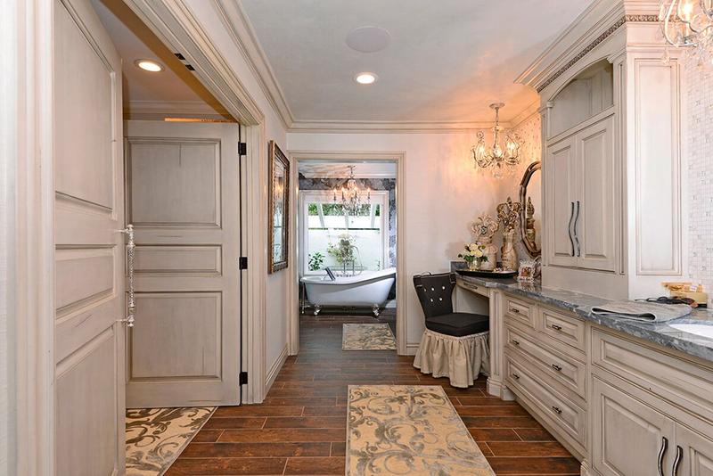 Elegant white hallway with built-in cabinets, a chandelier, tiled floor, and a view into a bright sitting area