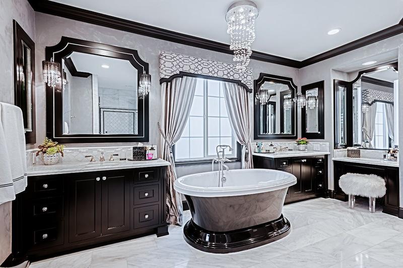 Elegant bathroom with dark wood vanities, oval tub, and large mirrors in a bright marble setting