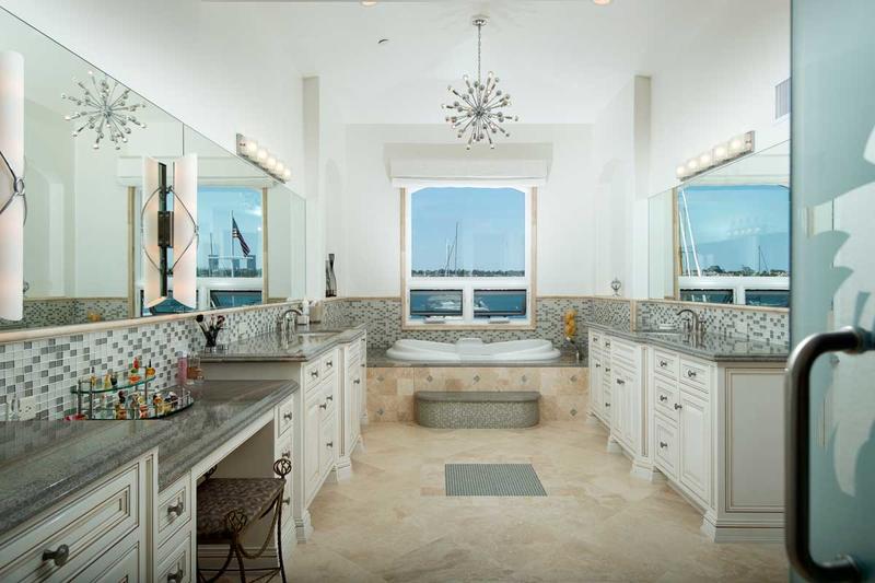 Bright beach-themed kitchen with white cabinets, mosaic counters, and ocean views through a central window