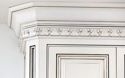 White ornate cabinet corner with crown molding and decorative trim
